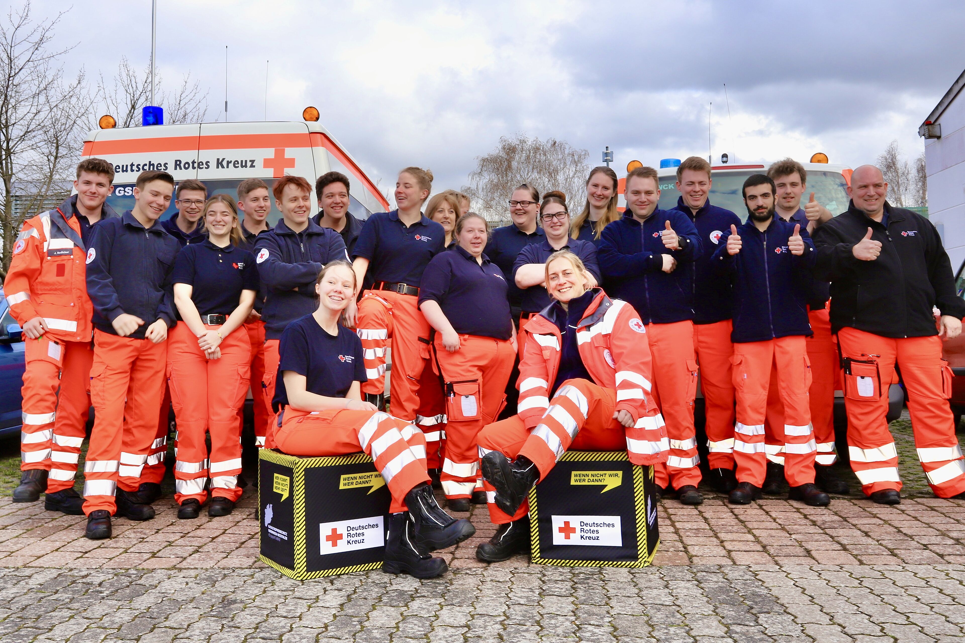 Zwanzig neue Sanitäter*innen stellen sich in bester Laune zum Gruppenfoto