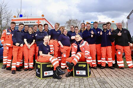 Zwanzig neue Sanitäter*innen stellen sich in bester Laune zum Gruppenfoto